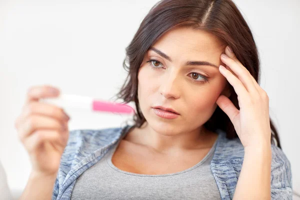 Traurige Frau schaut auf Schwangerschaftstest zu Hause — Stockfoto