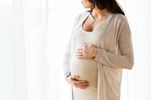 Крупним планом вагітна жінка дивиться у вікно — стокове фото