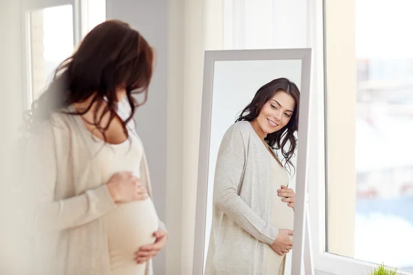 Heureuse femme enceinte qui cherche à miroir à la maison — Photo