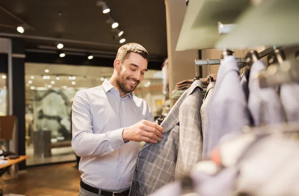 Gelukkig jonge man kiezen kleren in kledingwinkel — Stockfoto