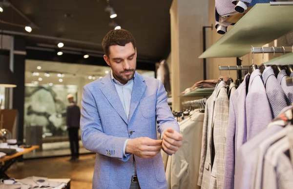 Glad ung man försöker jacka på i klädbutik — Stockfoto