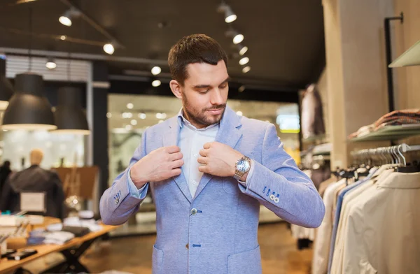 Щасливий молодий чоловік пробує піджак в магазині одягу — стокове фото