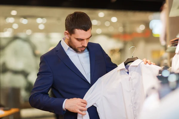 Glücklicher junger Mann wählt Kleidung im Bekleidungsgeschäft — Stockfoto