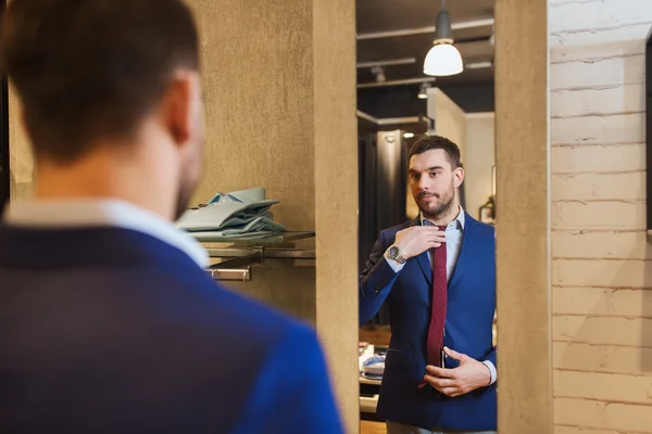 Muž se snaží kravatu na v zrcadle v obchod s oblečením — Stock fotografie