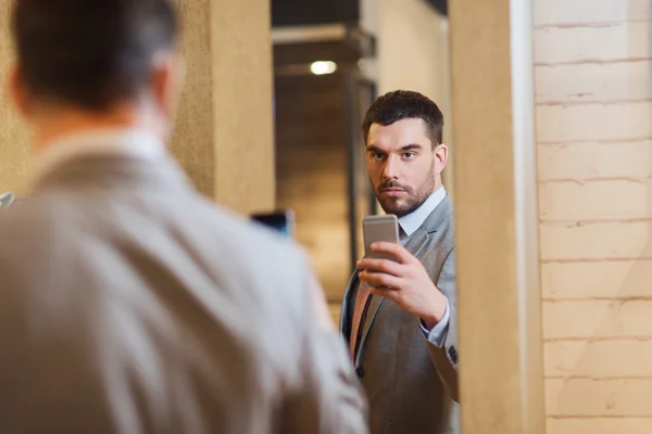 Человек в костюме делает зеркальное селфи в магазине одежды — стоковое фото