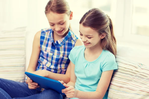 Happy girls with tablet pc sitting on sofa at home — Stock Photo, Image