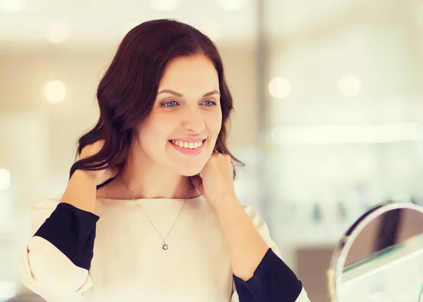 Happy woman choosing pendant at jewelry store — Stock Photo, Image