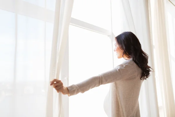 Primer plano de la mujer embarazada apertura de cortinas de ventana — Foto de Stock