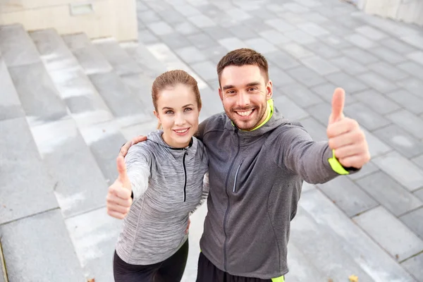 Sonriente pareja mostrando pulgares en la calle de la ciudad — Foto de Stock