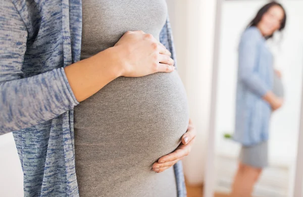 Närbild på gravid kvinna söker till spegel — Stockfoto