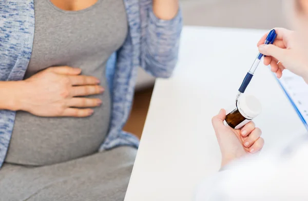 Крупный план врача, показывающего таблетки беременной женщине — стоковое фото