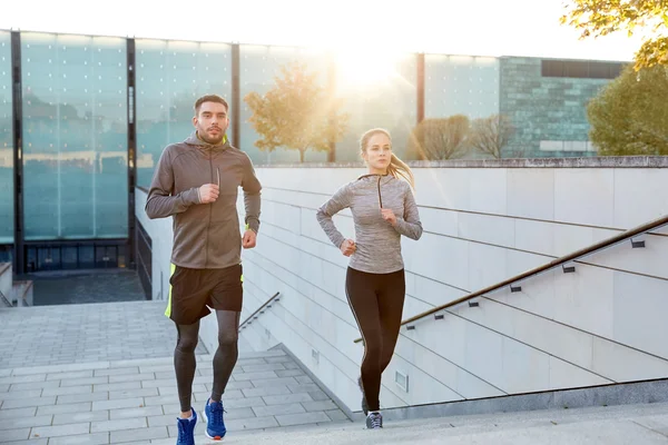 Feliz pareja corriendo arriba en la ciudad escaleras — Foto de Stock