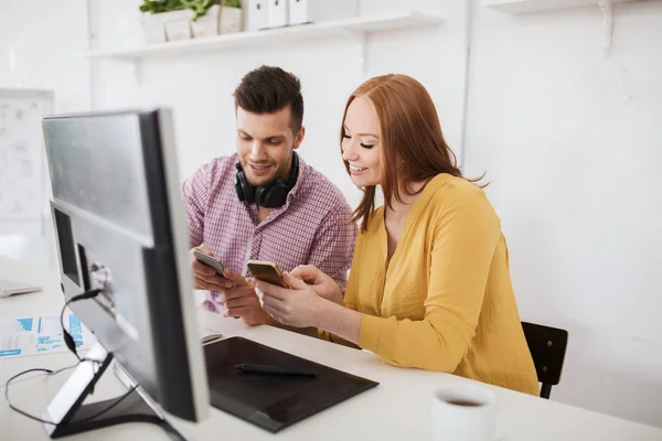 Equipo creativo feliz con teléfonos inteligentes en la oficina — Foto de Stock