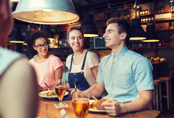 Happy friends eating and drinking at bar or pub — Stock Photo, Image