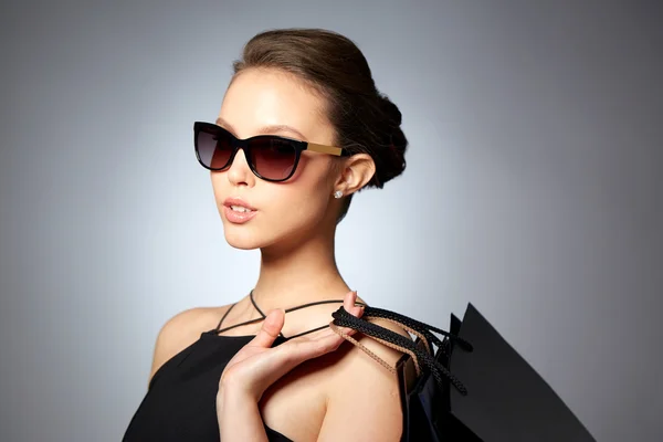 Mujer feliz en gafas de sol negras con bolsas de compras —  Fotos de Stock