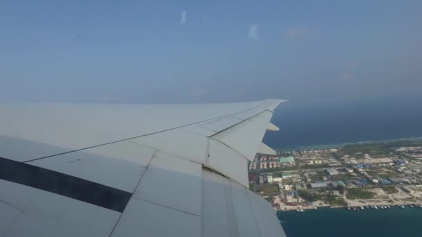 Wing of airplane flying above ocean and city — Stockvideo