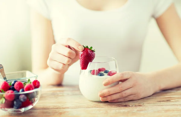 Närbild på kvinna händer med yoghurt och bär — Stockfoto