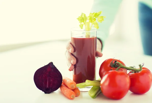 Close up of woman hands with juice and vegetables — Stock Photo, Image