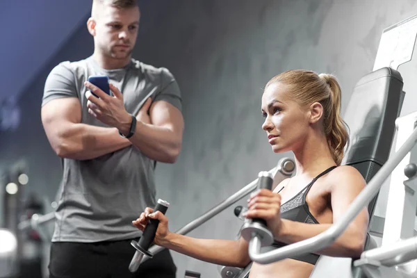 Hombres y mujeres flexionando los músculos en la máquina de gimnasio — Foto de Stock