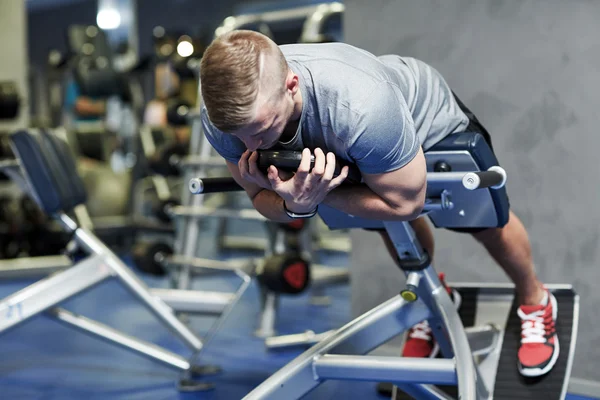 Young man flexing back muscles on bench in gym — Stock Photo, Image