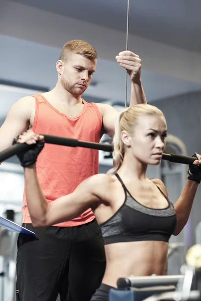 Man and woman flexing muscles on gym machine — Stock Photo, Image