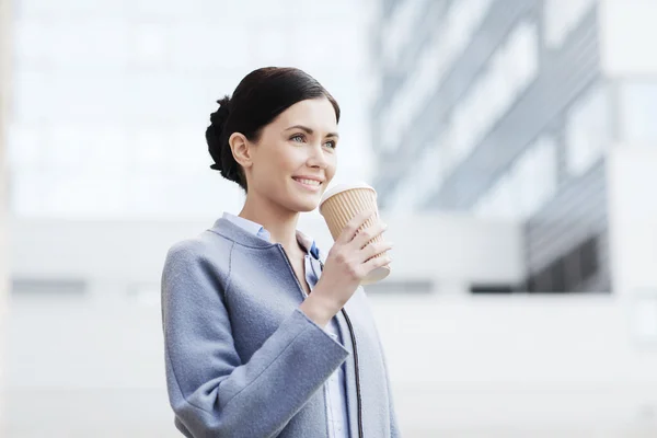 Leende kvinna dricka kaffe i city — Stockfoto