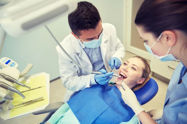 Стоматолог-мужчина лечит женские зубы пациента — стоковое фото