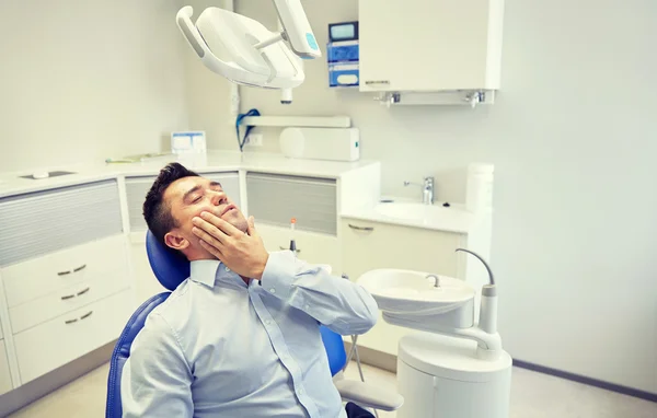 Homem com dor de dente e sentado na cadeira dental — Fotografia de Stock