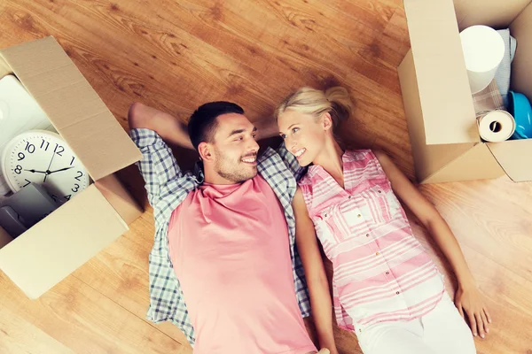 Happy couple lying on floor among cardboard boxes — Stok fotoğraf