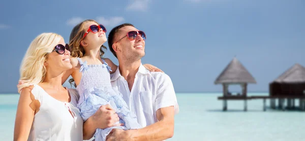 Счастливая семья над тропическим пляжем с бунгало — стоковое фото