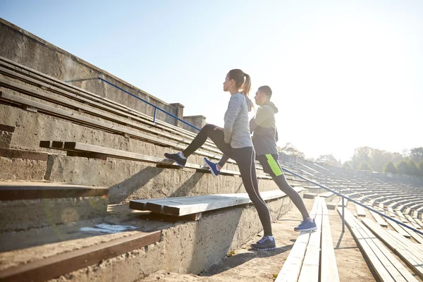 Paar stretching been op stands van stadion — Stockfoto