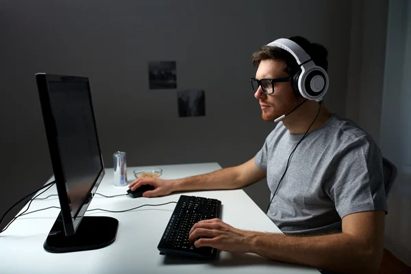 man in headset playing computer video game at home