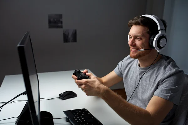 Hombre en auriculares jugando videojuego de ordenador en casa — Foto de Stock