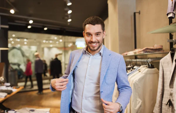 Šťastný mladý muž snaží bundu na v obchod s oblečením — Stock fotografie