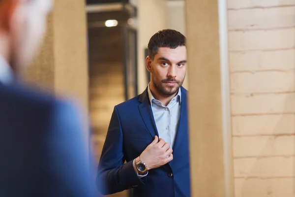 Man trying jacket on at mirror in clothing store — Stock Photo, Image