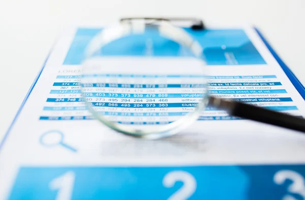 Close up of financial report and magnifying glass — Stock Photo, Image