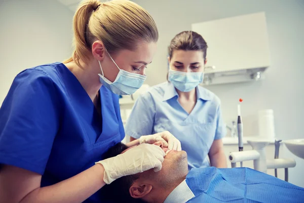 女性の歯科医が患者の歯の噛み合わせをチェック ストックフォト