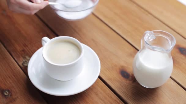 Рука наливає цукор чайною ложкою в чашку кави — стокове відео