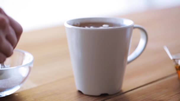 Hand adding sugar to cup of tea or coffee — Stock Video