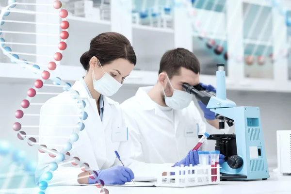 Científicos con portapapeles y microscopio en laboratorio — Foto de Stock