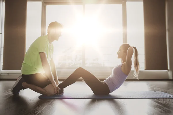 Mulher com personal trainer fazendo sit ups no ginásio — Fotografia de Stock