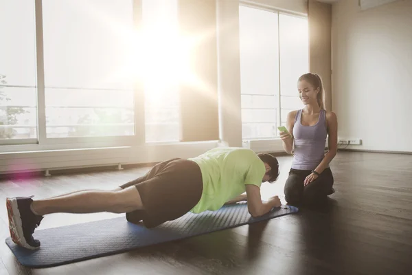 Homem e mulher fazendo exercício prancha no tapete no ginásio — Fotografia de Stock