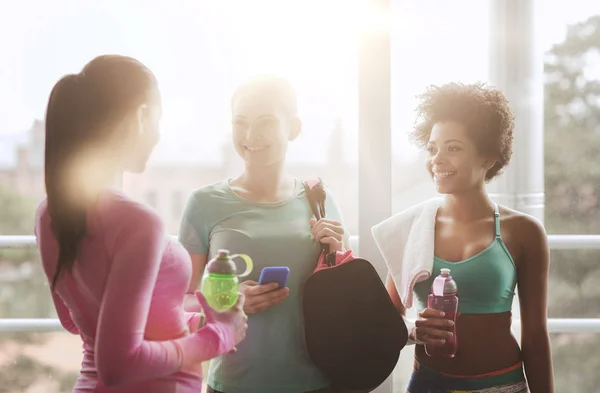 Happy women with bottles of water in gym — Stock Photo, Image