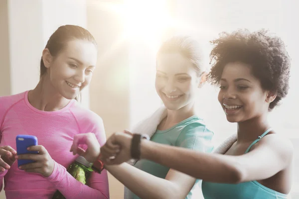 Mujeres felices mostrando tiempo en reloj de pulsera en el gimnasio — Foto de Stock