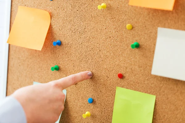 Hand pointing to cork board with stickers and pins — Stock Photo, Image