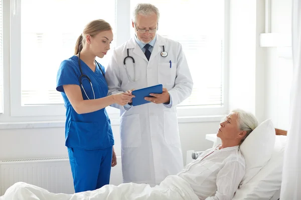Läkare och sjuksköterska besöker äldre kvinna på sjukhuset — Stockfoto