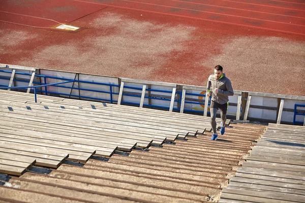 Jovem feliz correndo lá em cima no estádio — Fotografia de Stock