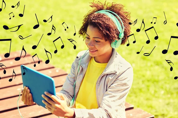 Gelukkig Afrikaanse vrouw in hoofdtelefoons met tablet pc — Stockfoto