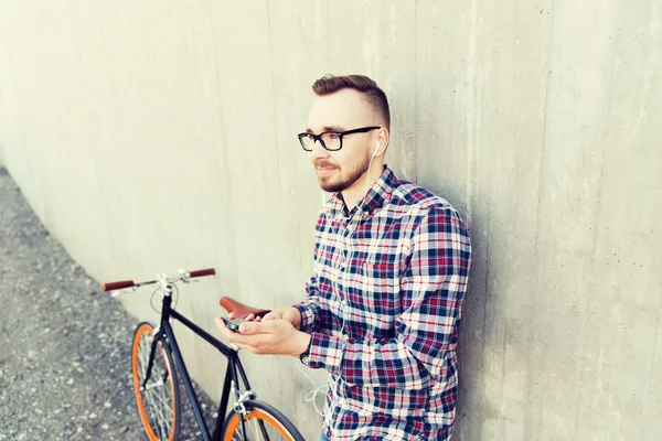 Homem hipster em fones de ouvido com smartphone e bicicleta — Fotografia de Stock