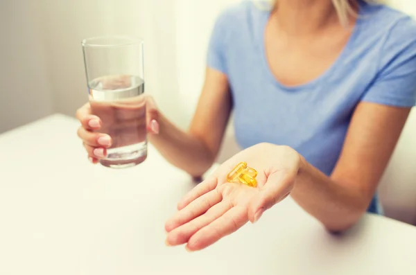 Primer plano de las manos de la mujer con cápsulas y agua — Foto de Stock